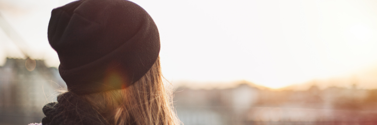 Things I Wish I Knew Earlier With Chronic Illness back of a girl's head, looking over a city during sunset