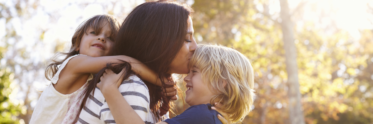 Being a Mom With Epilepsy and Anxiety Mother hugging her children in the park.