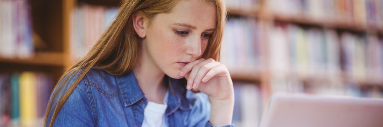 5 Ways to Balance Your Education and Illness in College A female college student sitting in a library, while using her computer.