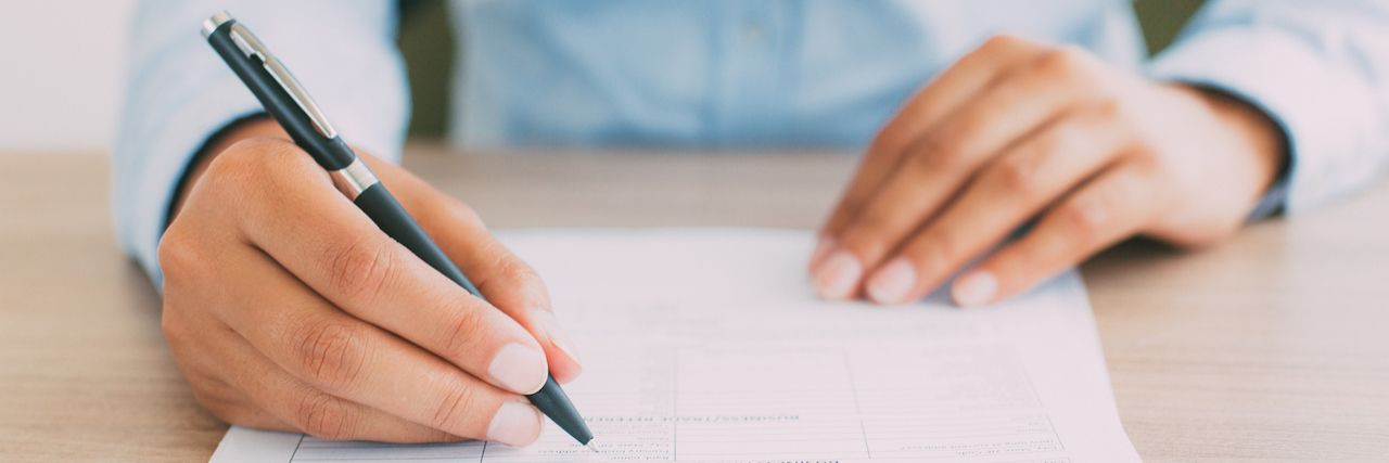 Why Job Hunting Sucks When You Have Anxiety and Depression Cropped view of person holding pen and filling out application form on table