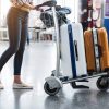woman pushing cart stacked with luggage through the airport