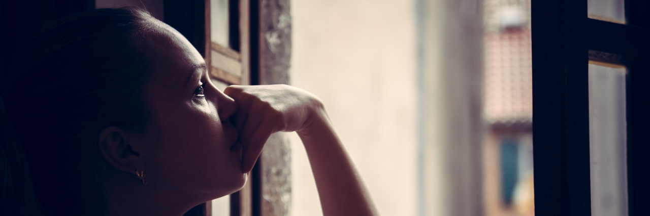 The Phases You Go Through After Your Child's Diagnosis young woman lost in thoughts, looking out the window