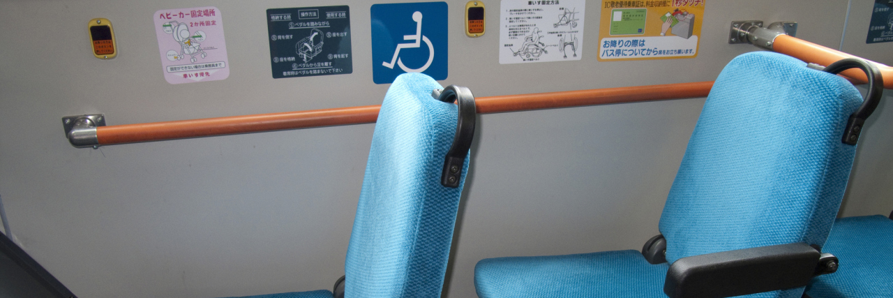 Sitting in a Disability Seat on the Tram as a Young Woman With Illness priority seats on a bus with the disability logo next to them