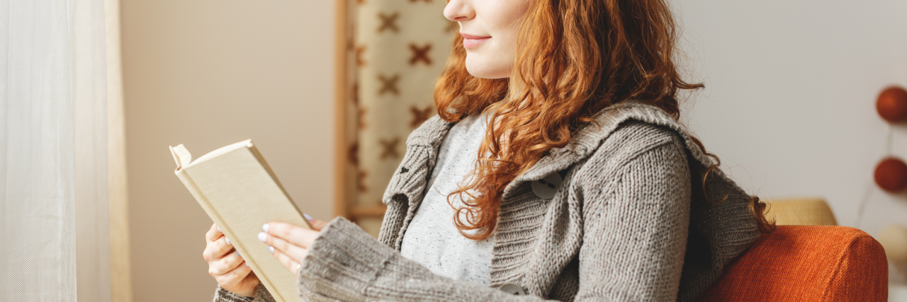 young redhead woman reading book and smiling