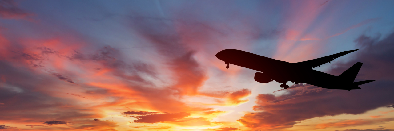 The Challenges of Air Travel With a Disability The silhouette of a passenger plane flying at sunset.