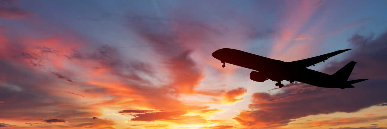 The silhouette of a passenger plane flying at sunset.