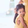 Sad asian child girl hugging her mother's leg
