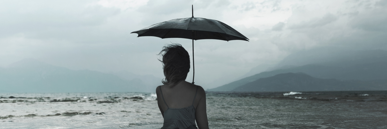 dreaming woman with umbrella waiting for the storm into the sea
