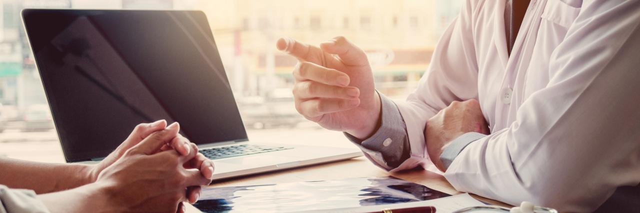 The Trauma and Anxiety of Doctor Appointments With Lyme Disease doctor sitting at his desk and talking with a patient