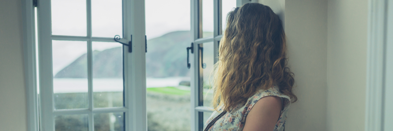 Life as a Chronically Ill 20-Something Doesn't Have to Suck A young woman looking out of her window.