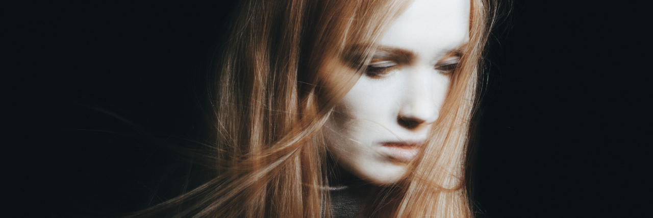 blurred photo of a woman with long red hair looking down and away