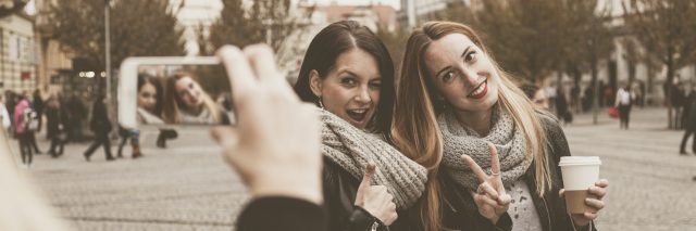 woman taking a photo of two friends posing and smiling