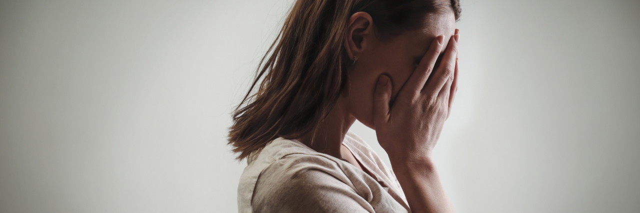 When Physical Symptoms of ME/CFS Mimic a Panic Attack side profile of a woman holding her face in her hands