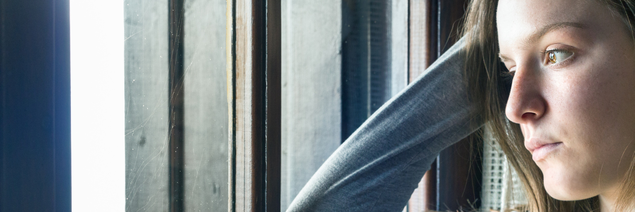 Chronic Illness Isn't a Reason to Feel Guilty A picture of a sad woman looking outside a window.