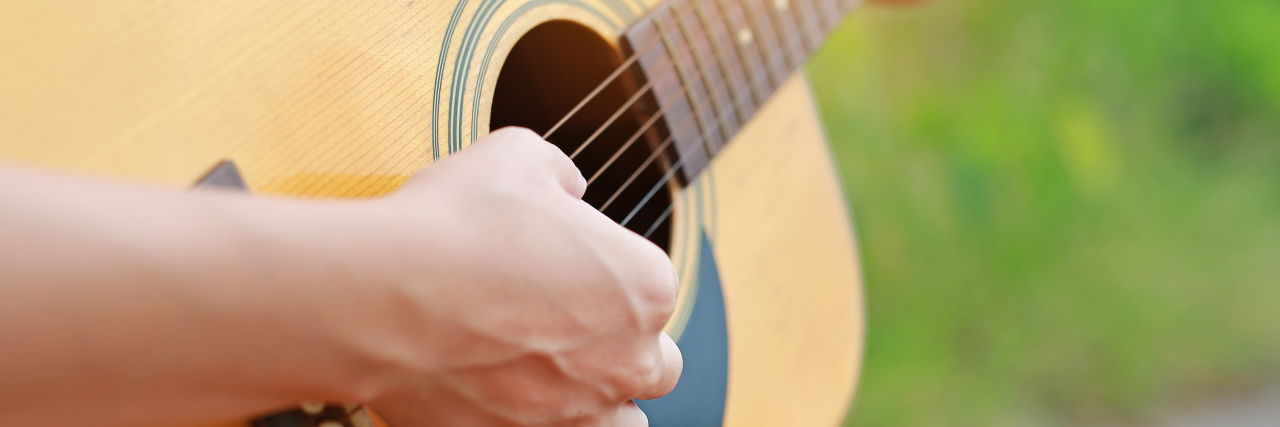 How Music Can Help Healing Hand playing acoustic guitar.