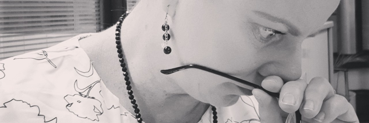 What a Day in the Life Looks Like for Someone With Chronic Pain black and white photo of a woman holding her glasses in front of her face and looking away