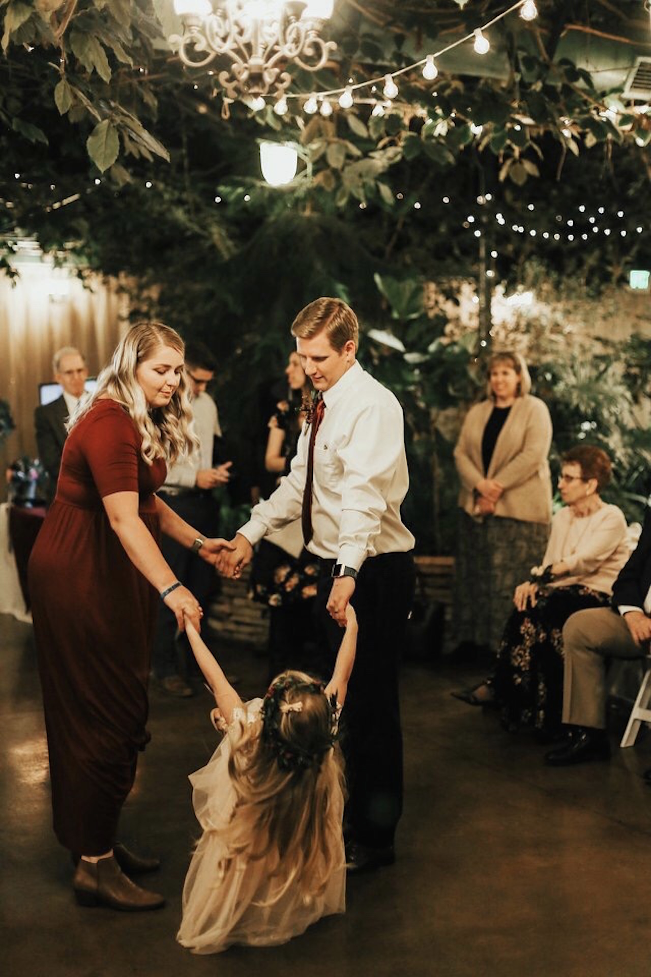 A photo of the writer dancing with a man and a child at a wedding.