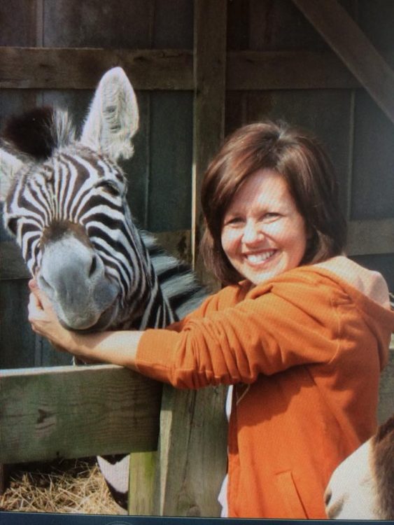 Joanne smiling next to a zebra