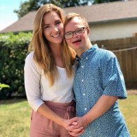 Image of Julia with twin brother Michael who has Down syndrome.They are huggig and holding hands smiling at camera.