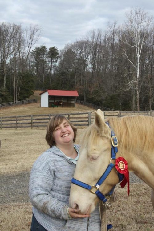 Julie standing next to her horse on a ranch and smiling