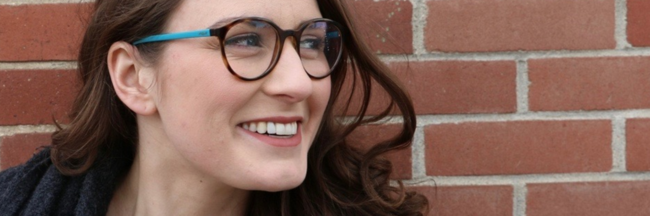 How My Mental Illness Changed My Life for the Better image of young woman smiling against brick wall with name overlaid