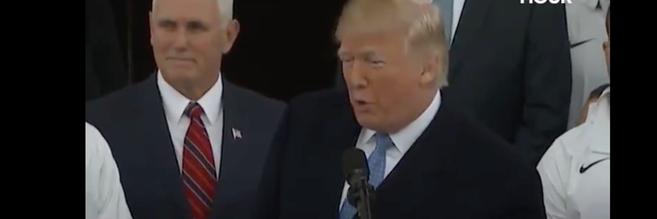 Photo of Trump addressing athletes. Pence is standing behind him.