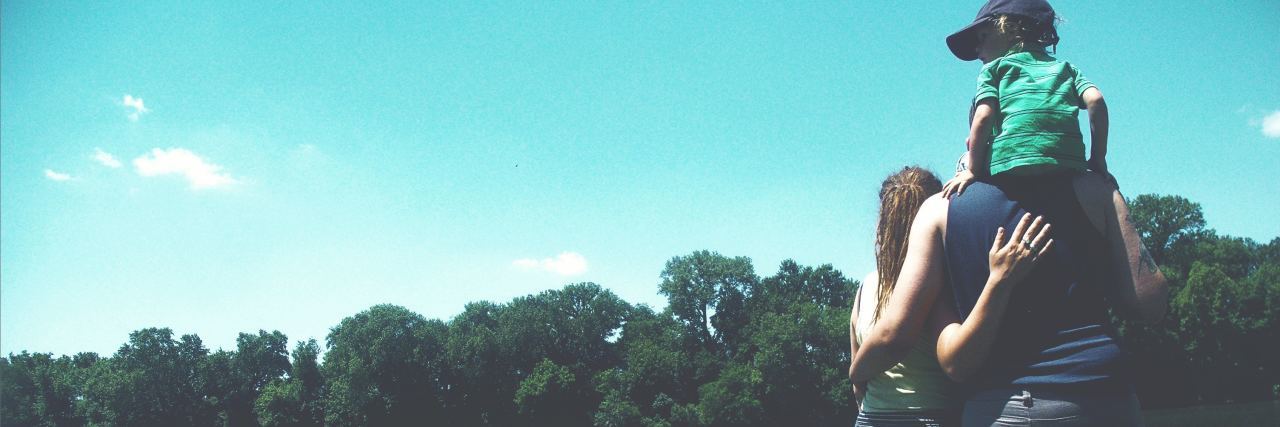 How to Help a Family With a Child Affected by Mental Illness family standing close together by lake on sunny day with blue sky