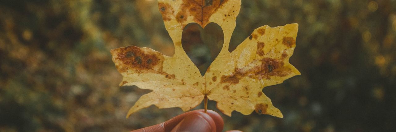 To the People Struggling With Mental Illness Today fall leaf held against sunset with heart cut out of it