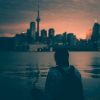 young woman wearing backpack looking at Toronto skyline at sunset