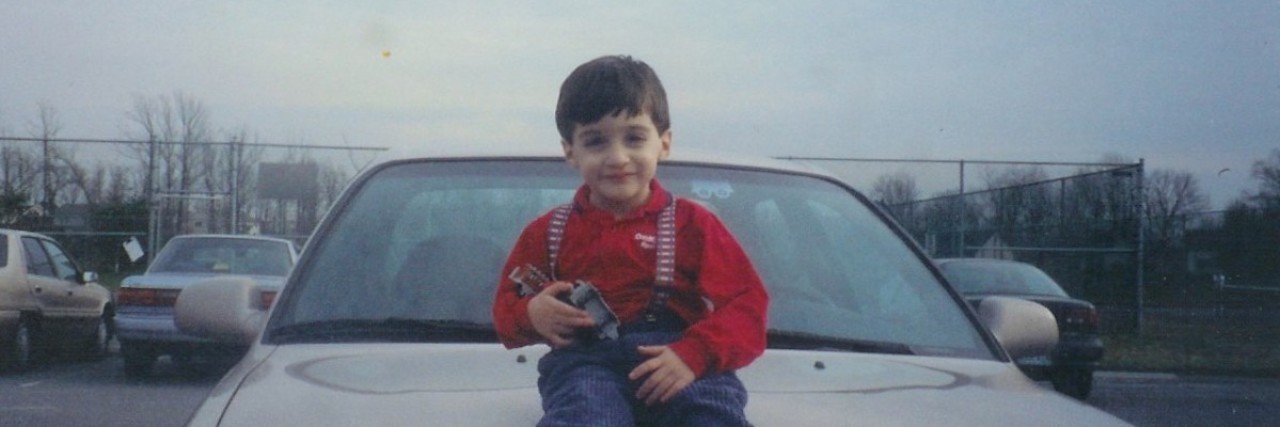 Boy holding train while sitting on a car