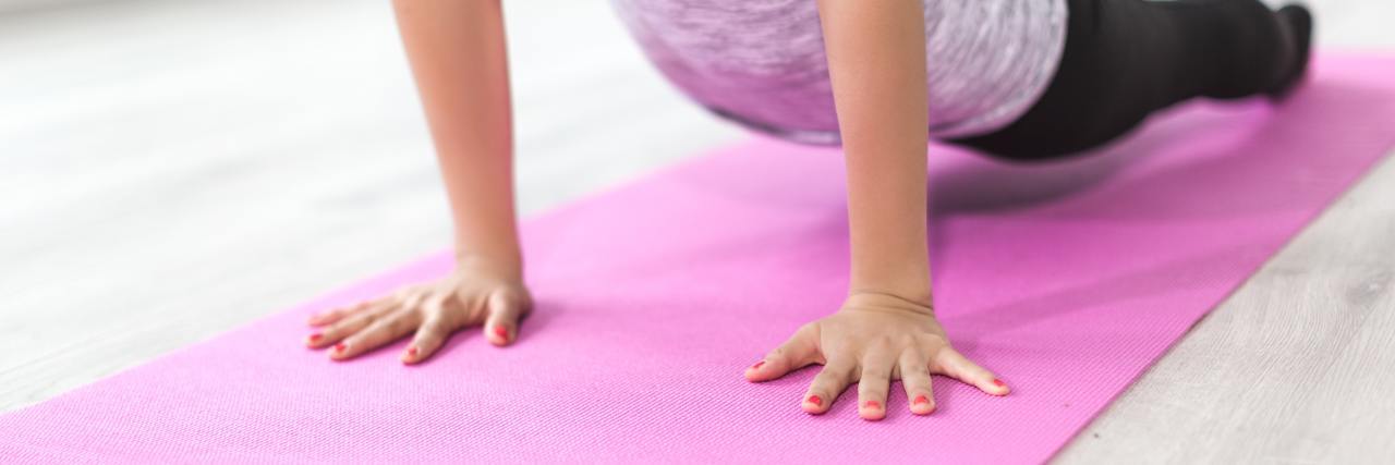 How I Exercise With Migraine woman doing yoga on a pink mat