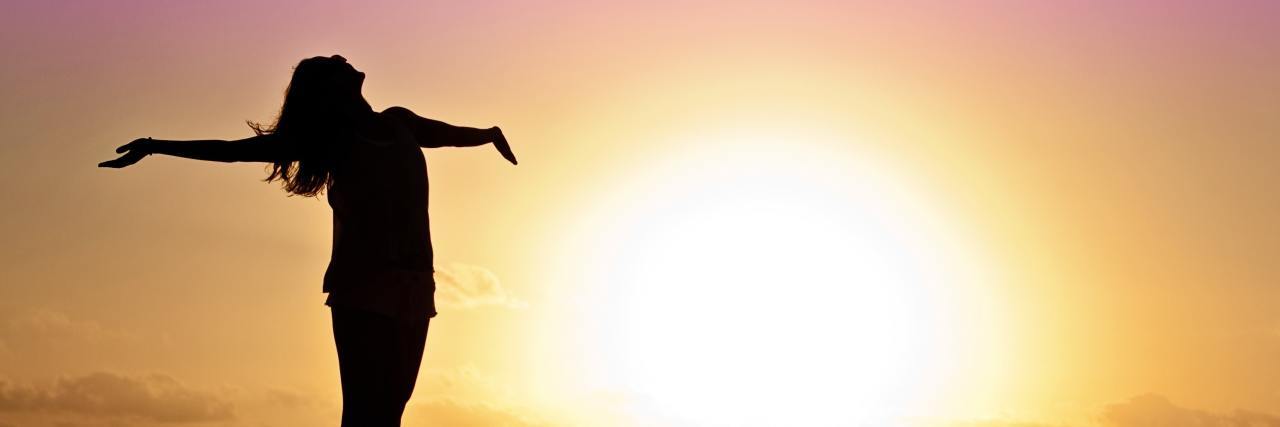 How to Manage Chronic Illness During the Heat of Summer silhouette of a woman standing by the ocean at sunset