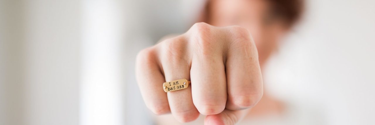 Why Having a Mental Illness Makes You a Badass woman with fist towards camera showing ring that says I am badass