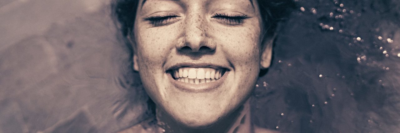 Woman lying in ocean and smiling close up