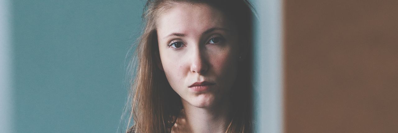 When You Have to Call 911 for a Suicidal Parent A woman peeking from behind a door