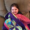 young girl smiling with quilt