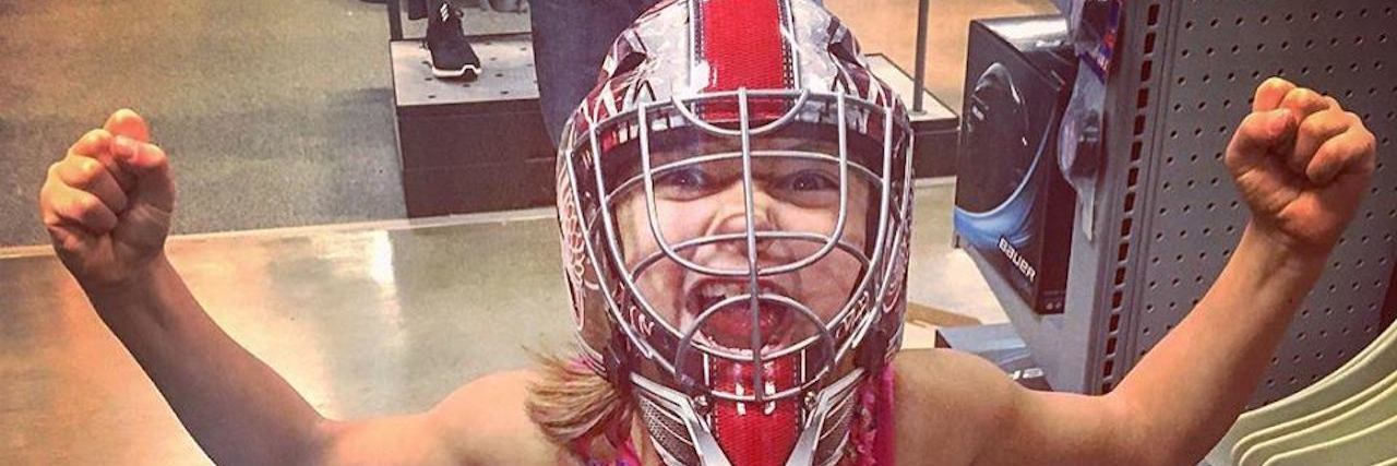 My Daughter's Autism Changed My Life -- For Good Little girl wearing a fancy pink dress and a football helmet, showing her muscles and making a "fierce" face