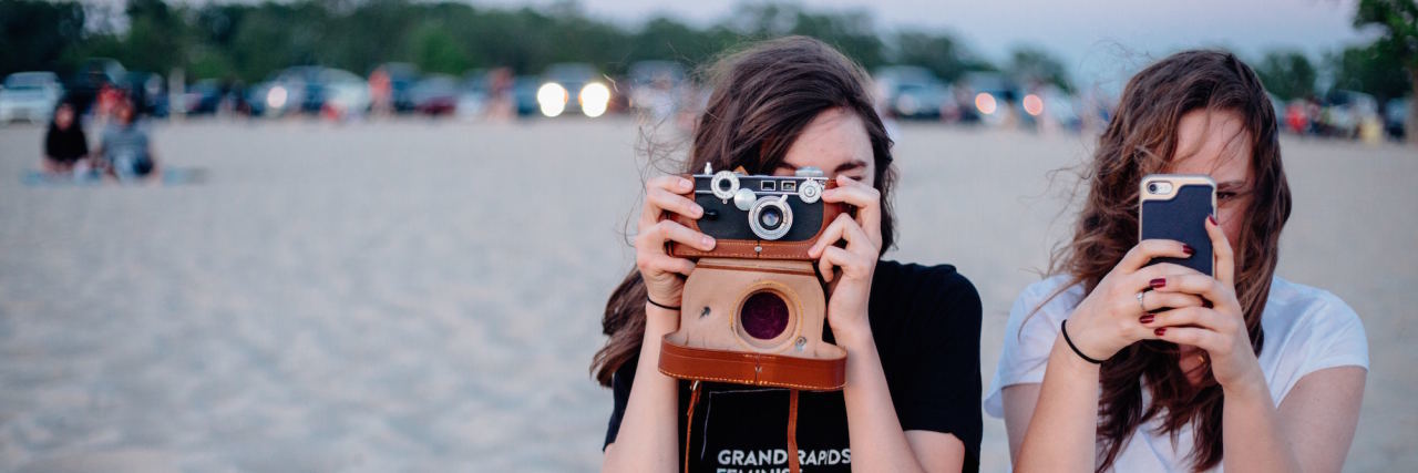 5 Things to Know About Being the 'Favorite Person' of Someone With BPD Two girls on a beach are holding cameras, taking photos of the viewer.