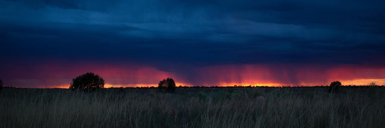 The Difficulties of Living With Comorbid Mental Illnesses photo of storm on horizon across field at sunset