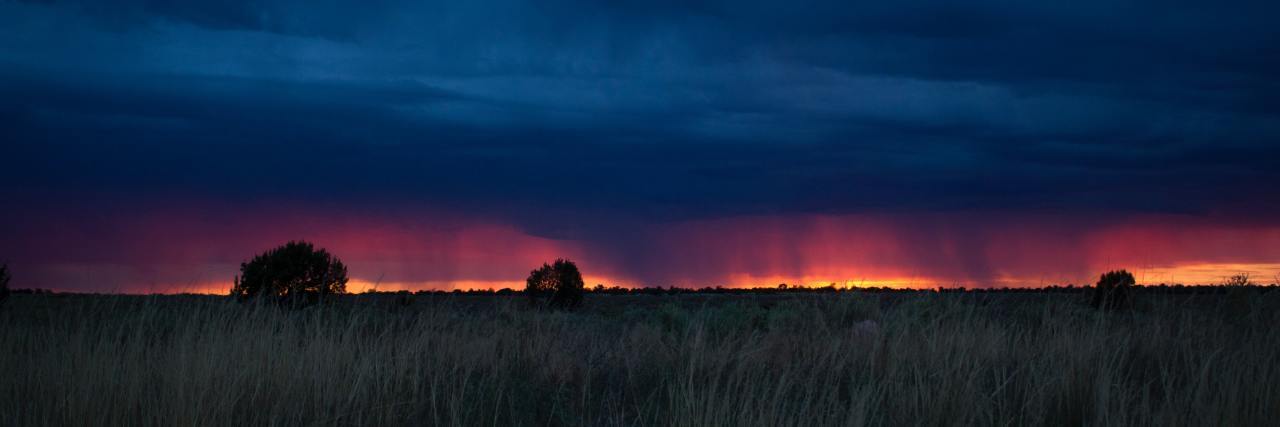 photo of storm on horizon across field at sunset