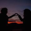 Two friends holding up their hands making a heart