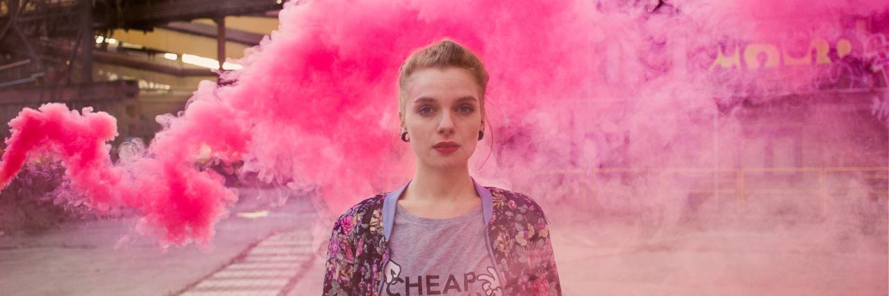 woman standing in front of a cloud of pink smoke