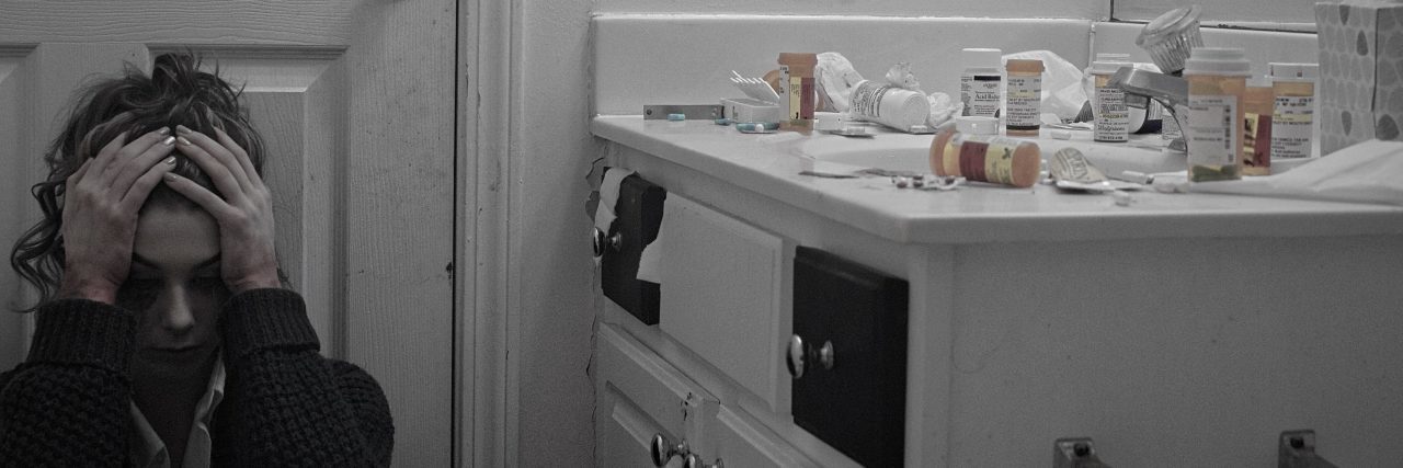 What to Know About Finding the Right Psychiatric Medication woman sitting on floor upset next to table with medication