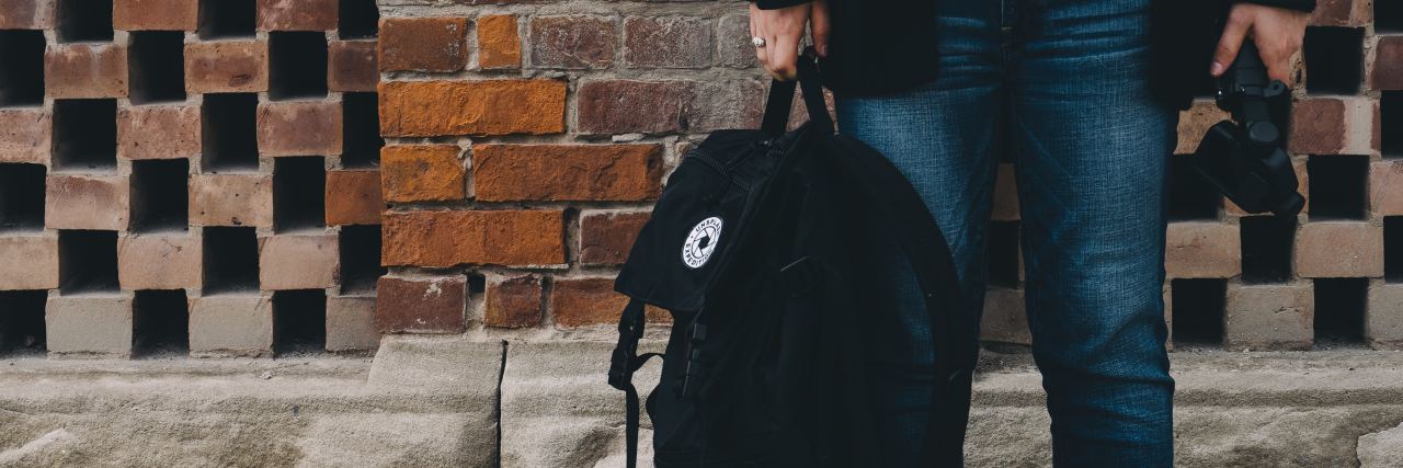 To the Student Being Treated Like the Next School Shooter A woman holding a backpack