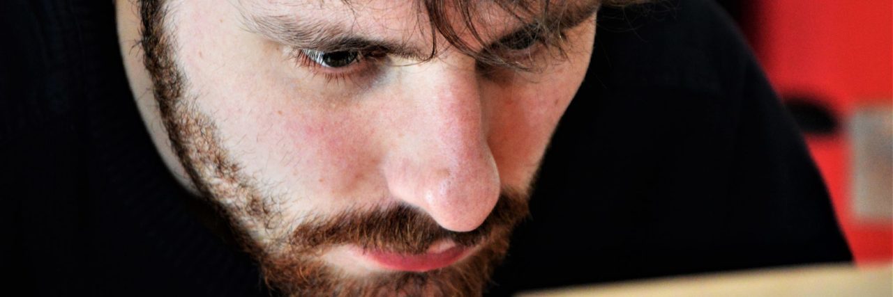 Why It Was Hard to Seek Mental Health Therapy as a Therapist sad depressed man with beard looking closely at laptop