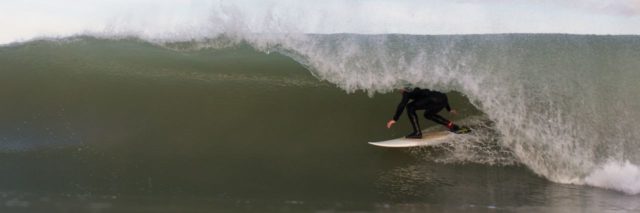 photo of surfer hidden by crashing wave