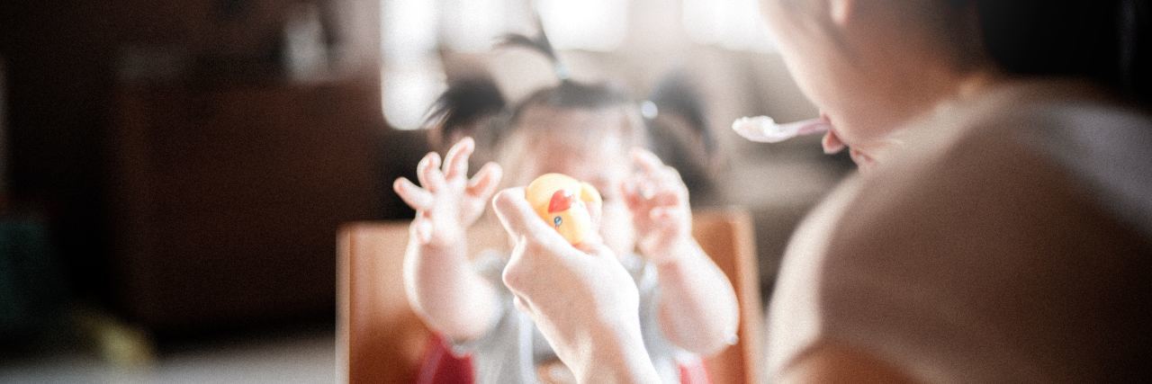 Letter to Other Mothers With Bipolar Disorder mother feeding young baby girl and holding rubber duck