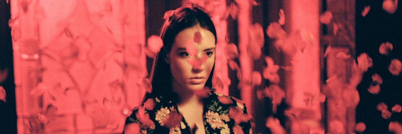 When My Mental Illnesses Convince Me I Need Them woman surrounded by red floating flower petals