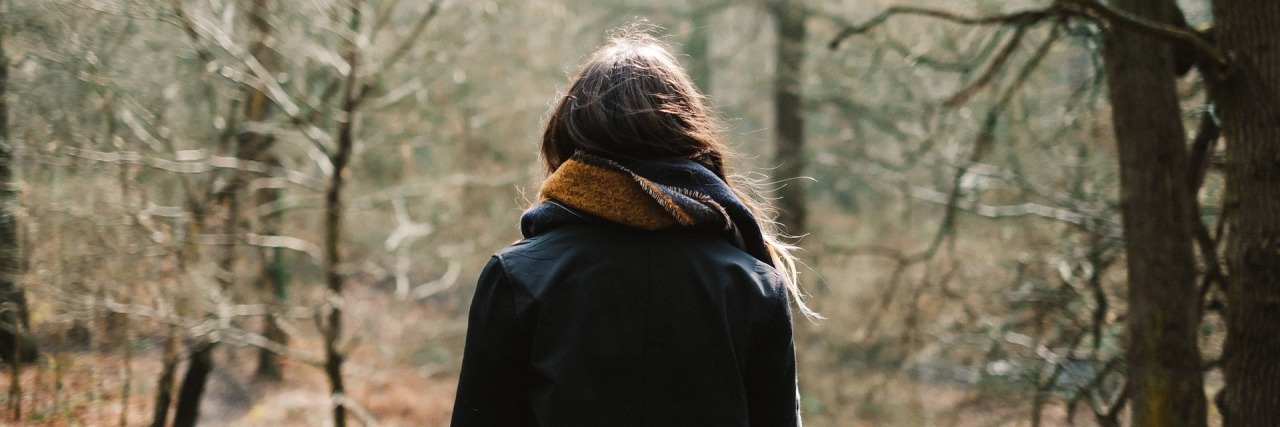 Hard Words to Hear When You Live with Chronic Pain girl with a coat and scarf standing in the woods