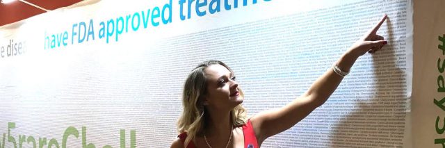 The author pointing to "adrenoleukodystrophy" on a wall about rare diseases